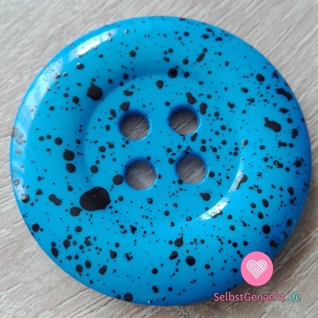 Mega großer blauer Knopf mit schwarzen Spritzern