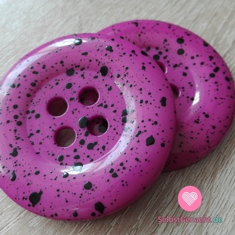 Mega großer lila-pinker Knopf mit schwarzen Spritzern