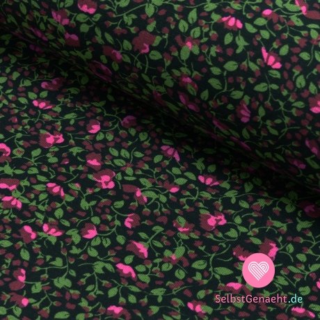 Strickdruck einer winzigen rosa Blume zwischen den grünen Blütenblättern auf Schwarz